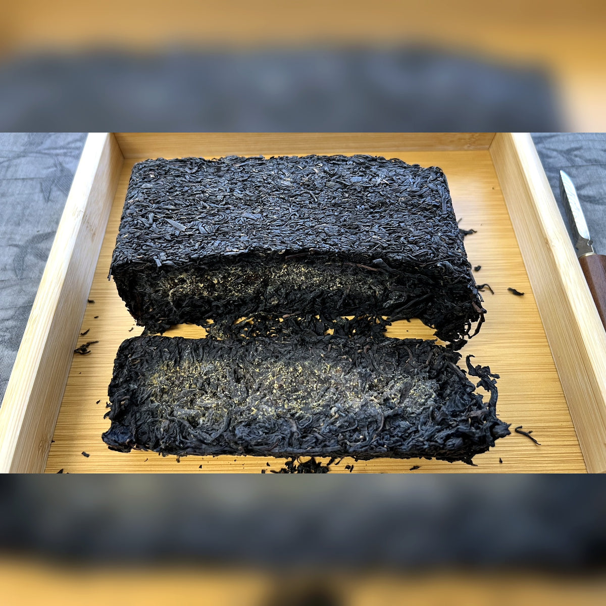 Golden Flower Fu Tea Brick opened on a wooden tray showing dark tea and golden flecks